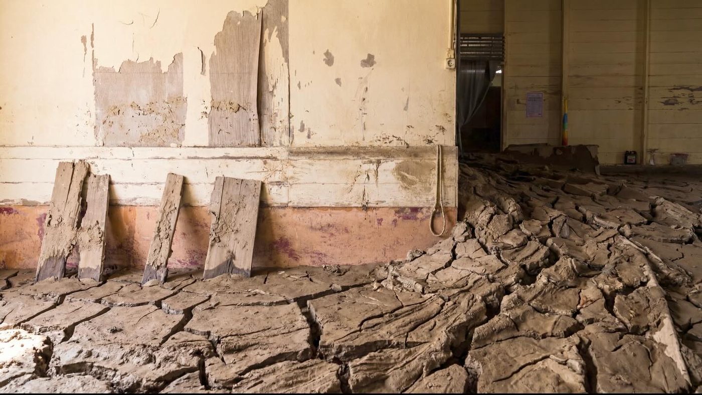 Inside a house, the floor covered in dried, cracked mud
