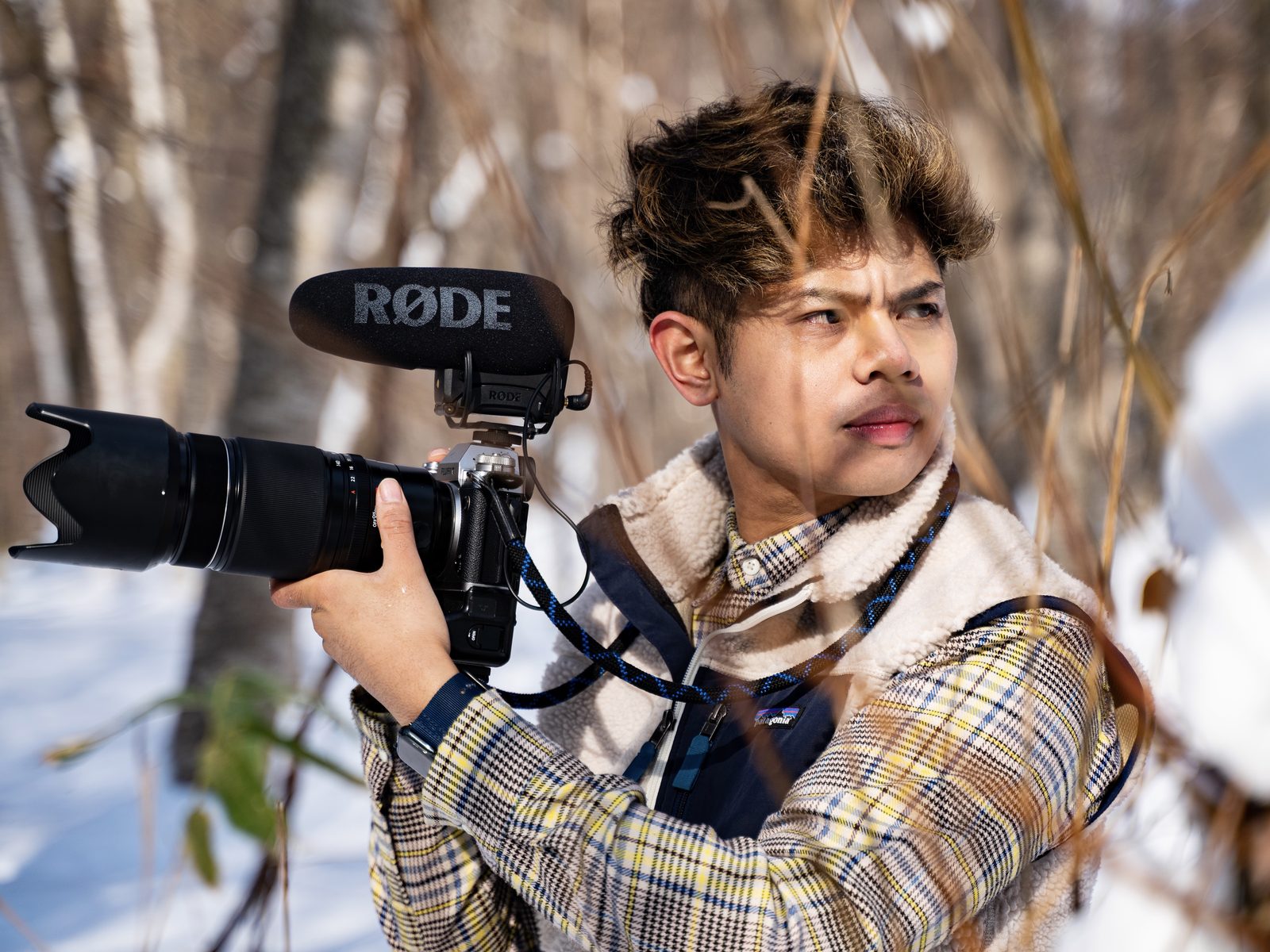 Narita Jun with a camera and microphone among snowy branches