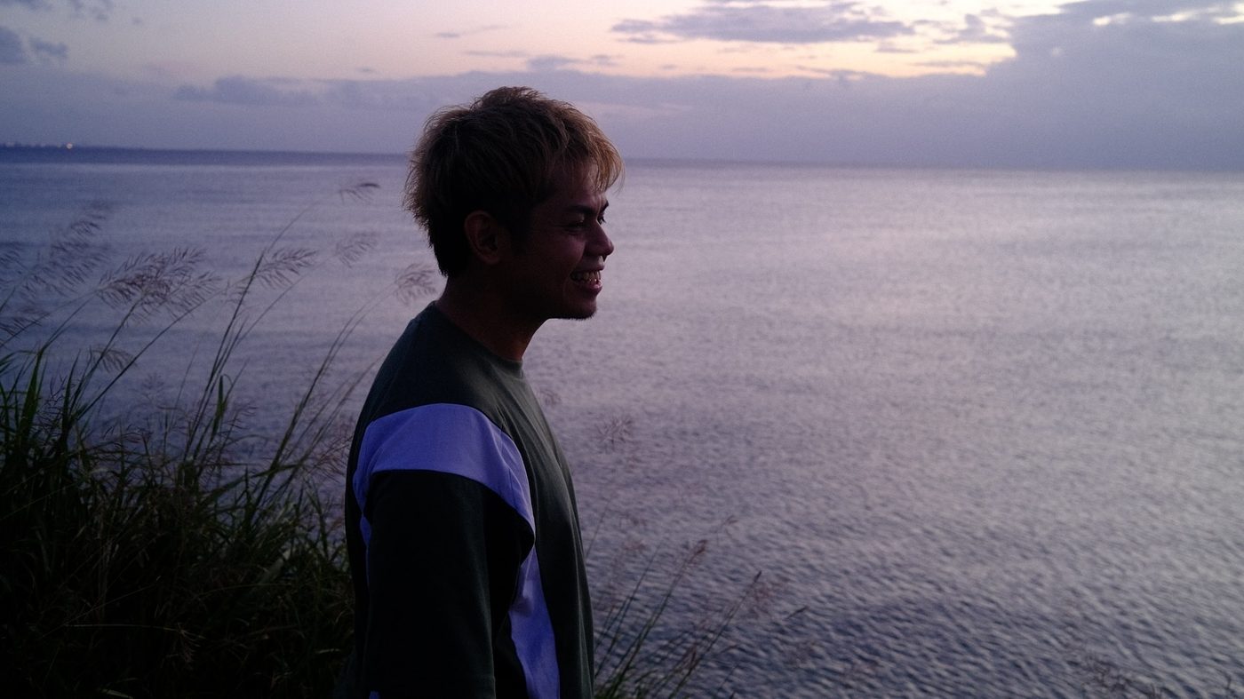 Narita Jun in profile, looking at the sea at dusk