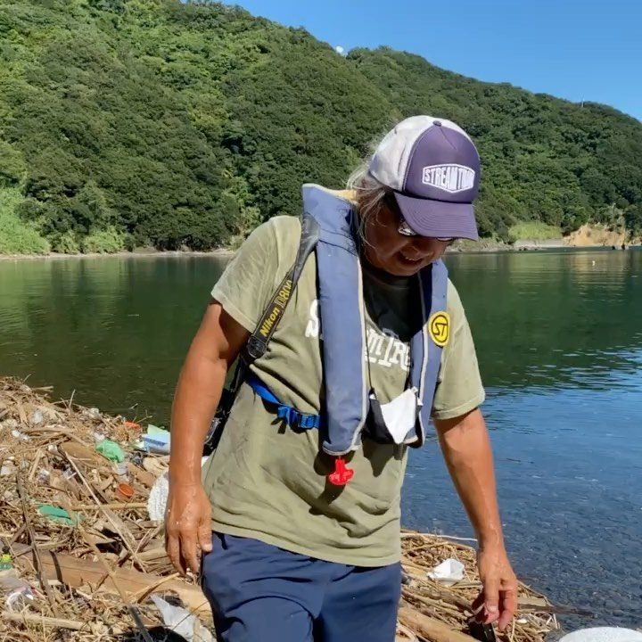 Mr. Iwata working on a beach strewn with driftwood and plastic waste