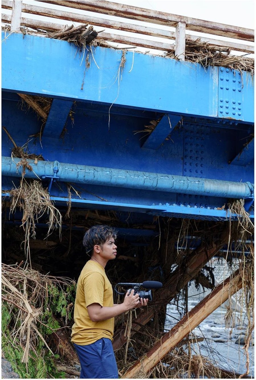 Narita Jun with his camera under a bridge caught with driftwood
