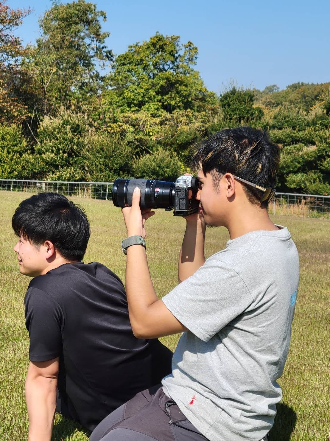 Narita Jun kneeling on the grass with his camera