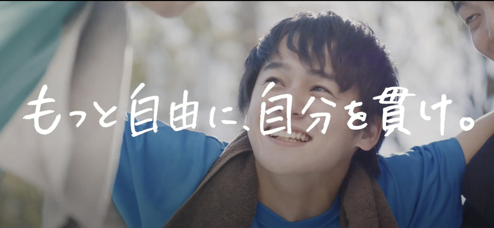 A young person laughing in a blue T-shirt, with the words “Be freer. Stay true to yourself.”